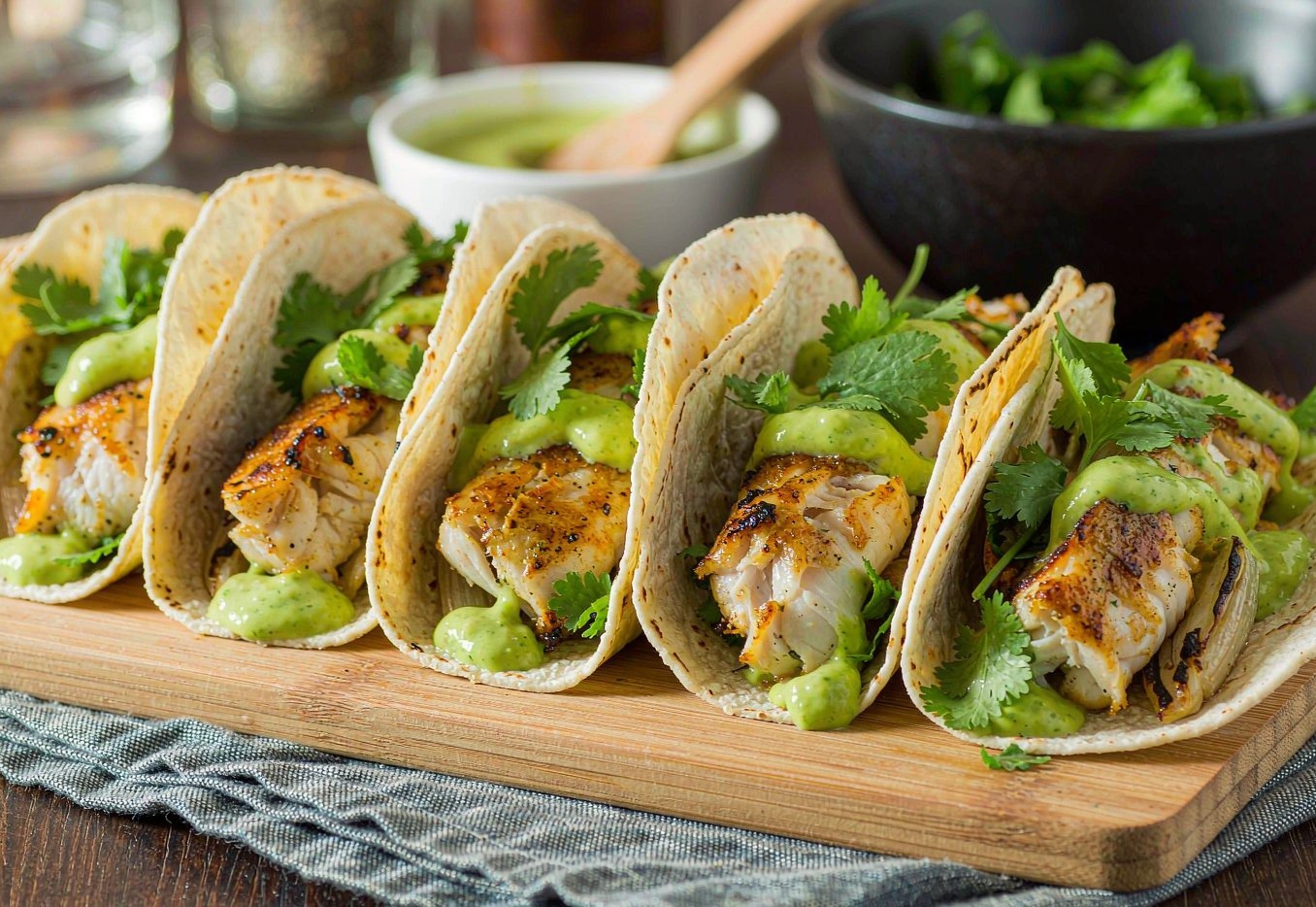 Pan-seared cod tacos topped with green avocado crema and cilantro