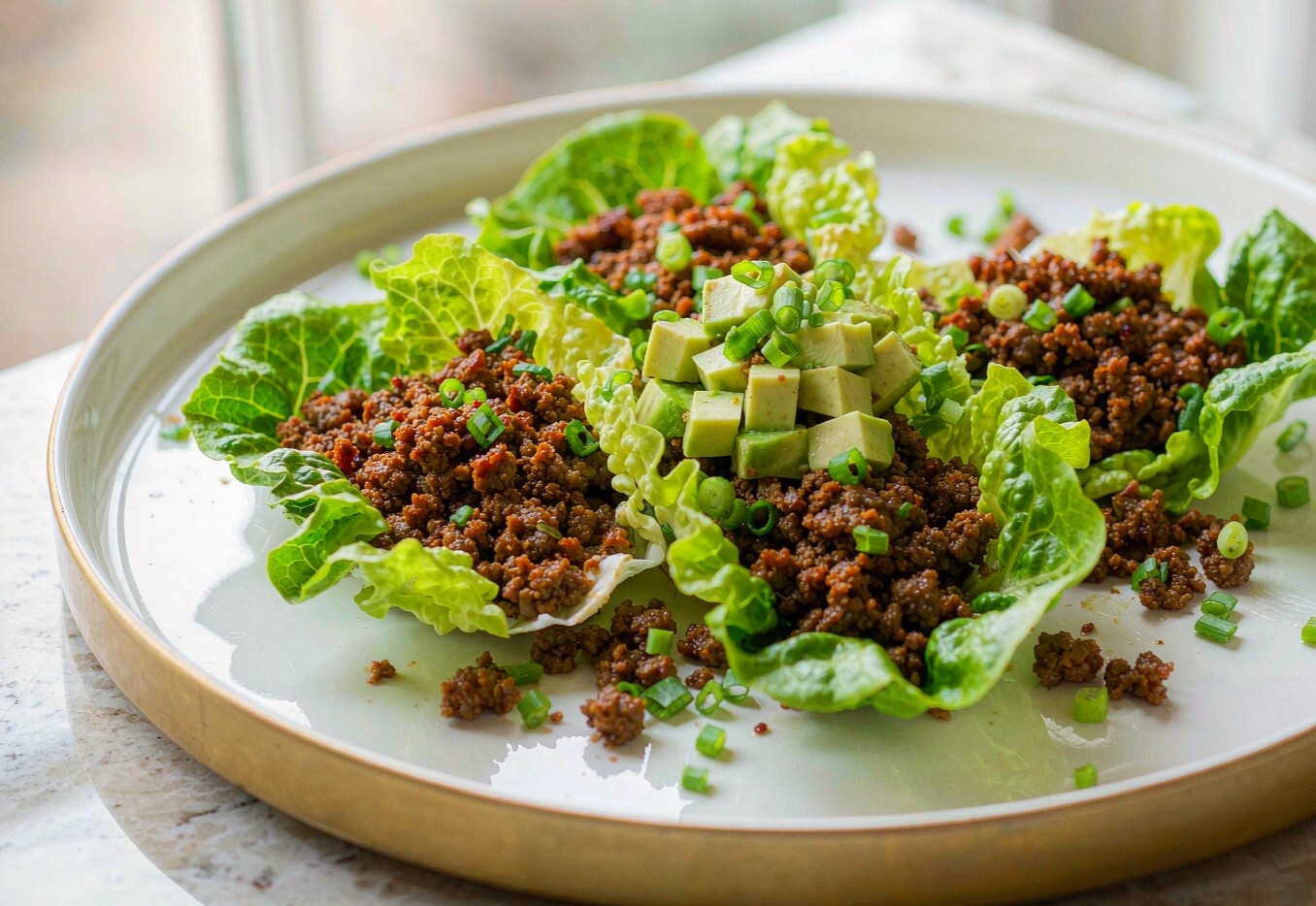Crispy ground beef in butter lettuce cups topped with diced avocado and scallions