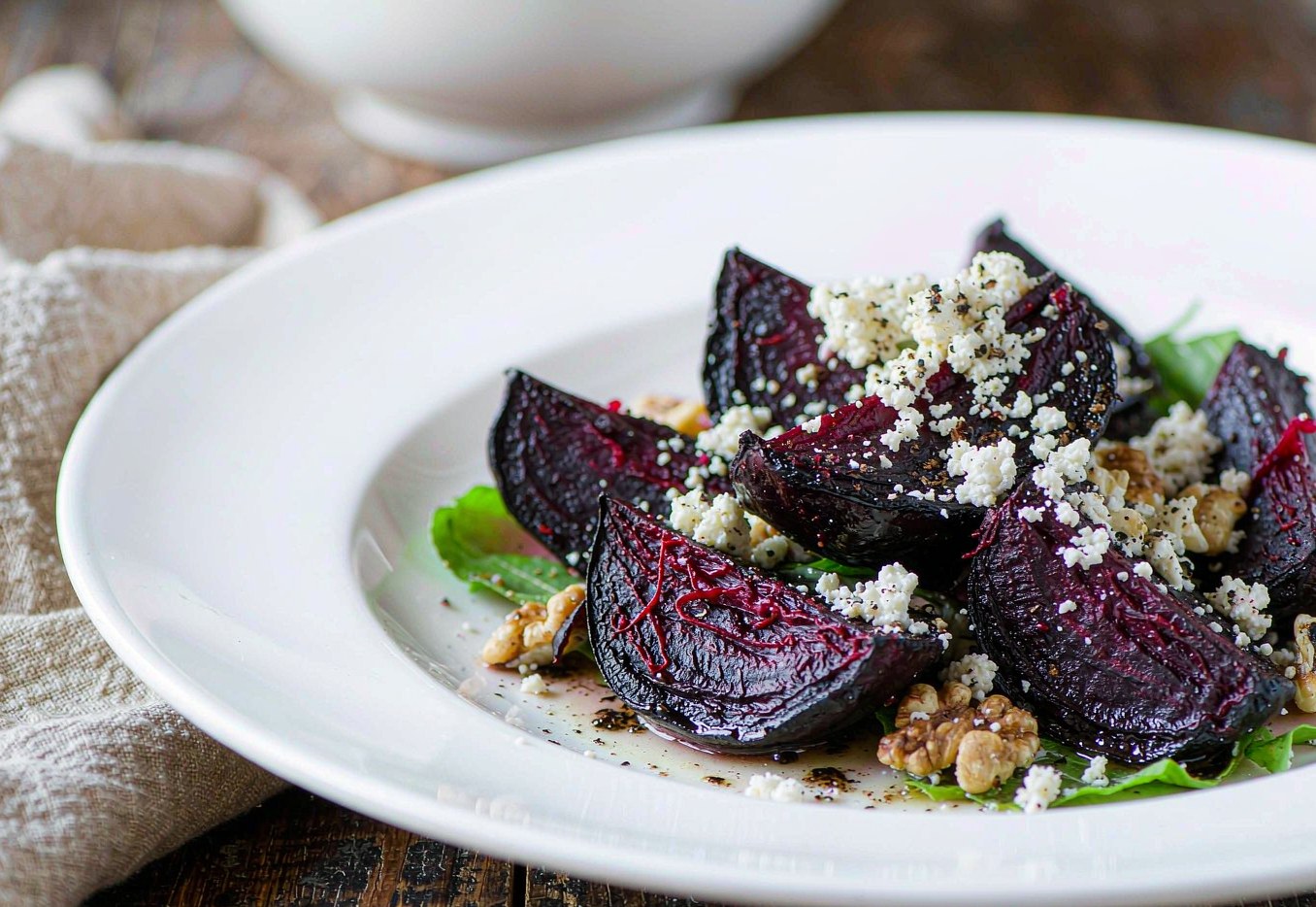 Roasted beet wedges arranged with crumbled goat cheese walnuts and salad greens